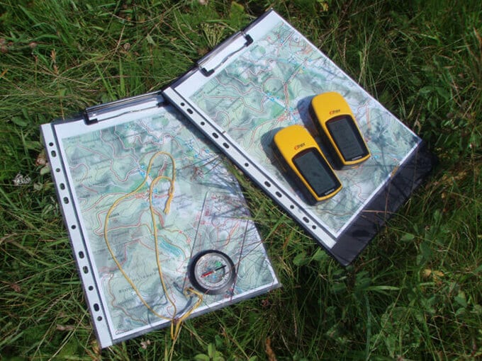 Topografische Karten mit Kompass und GPS-Geräten im Gras