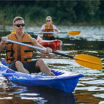 Zwei Personen beim Kajakfahren auf einem Fluss.